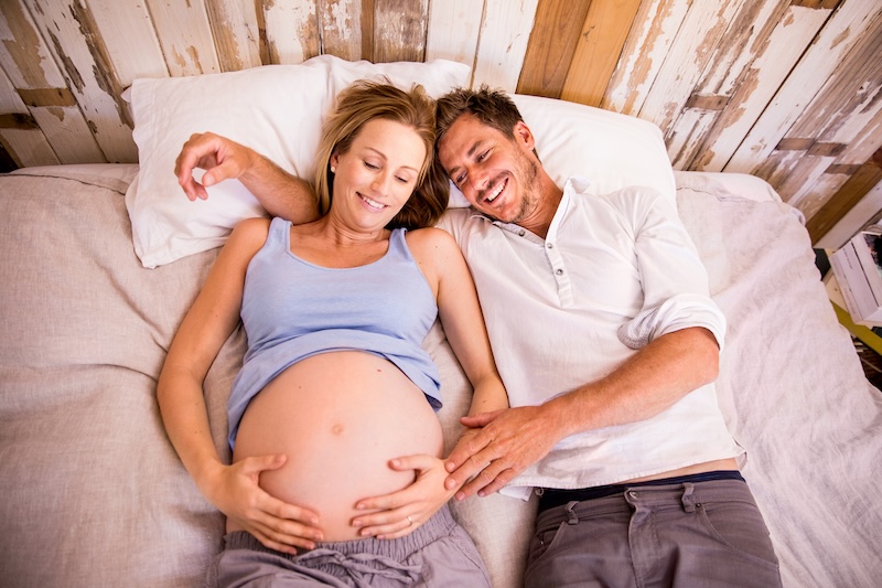Zwangere vrouw met partner liggend op bed